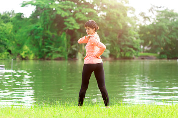 Young female workout before fitness training session at the park. Healthy young woman warming up outdoors.