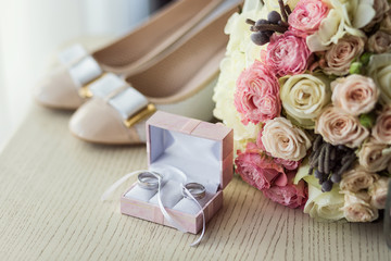 wedding rings lie near beautiful bouquet as bridal accessories