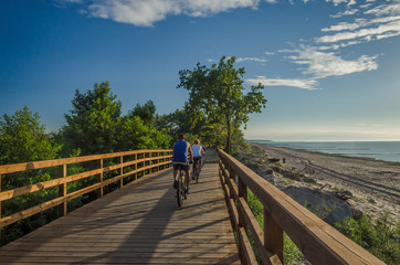 HOLIDAY SUNSET -  Holidaymakers on bike path by the sea shore