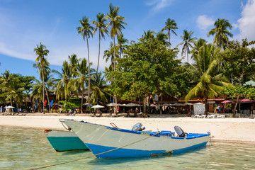 Lovely white beach with palm trees. Boats on the beach of a tropical island. Philippines. Asia