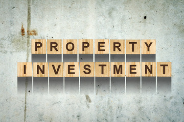 Words, Property Investment, consisting of letters on wooden cubes for construction on the background of an old concrete wall. Concept business