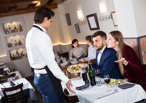 angry guests conflicting with waiter in restaurant