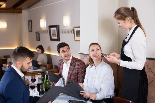 Positive waitress taking order from visitors