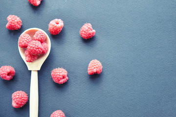 Fototapeta na wymiar Fresh organic raspberries on black background. berries on a wooden spoon