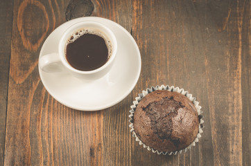 cup of black coffee and a chocolate muffin/cup of black coffee and a chocolate muffin on a dark wooden background. Top view