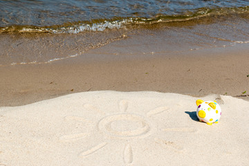 Obraz premium Urlaubsgeld - Botschaft im Sand mit Sparschwein