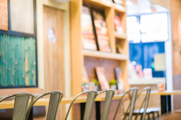 many seat steel chair and wooden table in fast food.beautiful interior at fast food.many seat for custumer sit and eating in fast food shop.custumer standing order food to cashier background.