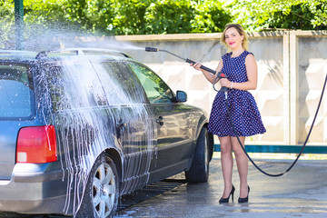pretty girl washes a car in a self-service washroom