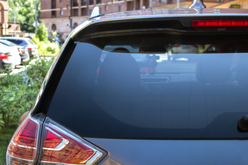 Naklejka premium Tylne okno samochodu zaparkowanego na ulicy w słoneczny letni dzień, widok z tyłu. Makieta do naklejek lub naklejek