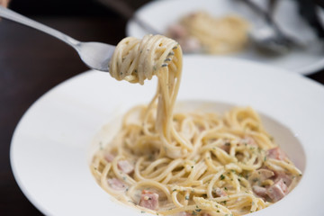 spaghetti carbonara on fork in italian restaurant