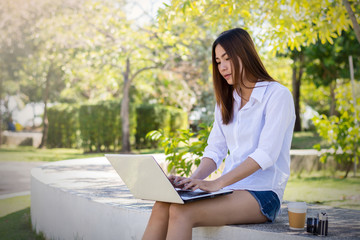 Young woman is using a laptop in the park.