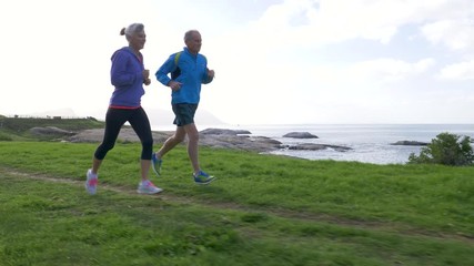 Senior couple jogging together by the sea