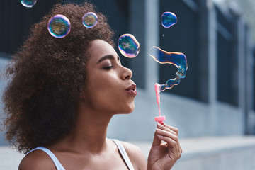 Young woman free style on the street sitting blowing bubbles joy
