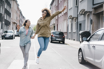 Best friends having fun in the city, running at jumping
