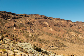 View of landscape of Teide National Park on Tenerife, Canarias islands, Spain. Yellow and black sand and distance view of mountains roads and volcano.