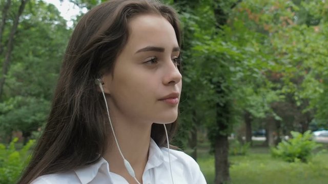Beautiful girl listening to music on headphones. The girl in headphones touches hair.