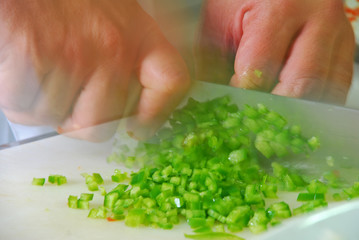 Hand with knife slicing chili