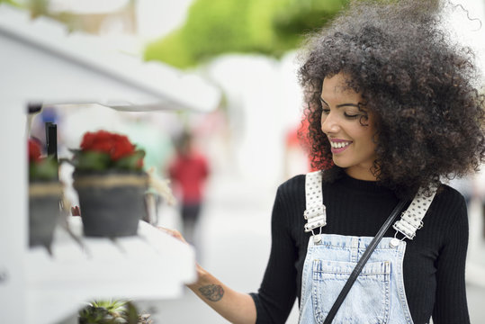 Smiling young woman watching potted plants of a flower shop