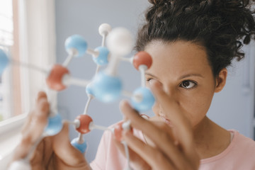 Female scientist holding molecule model, looking for solutions