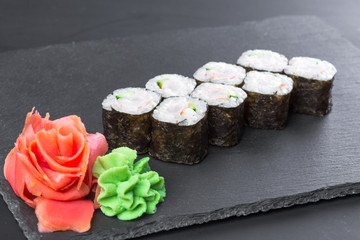 Japanese restaurant, sushi roll on black slate plate.