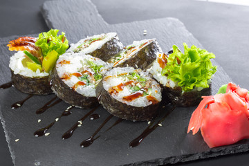Japanese restaurant, sushi roll on black slate plate.