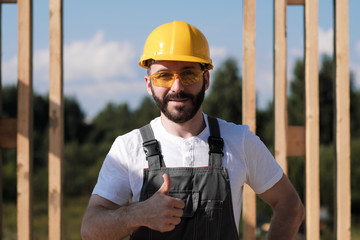 The man is a builder on the roof of a wooden frame house.
