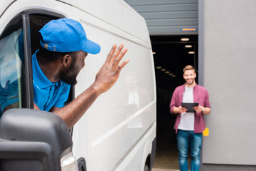 african american courier waving hand to client