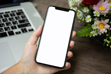 female hand holding phone isolated screen over desk with laptop