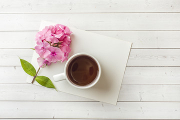 Fototapeta na wymiar Pink Phlox flowers and a Cup of coffee on a white table. Free space for text