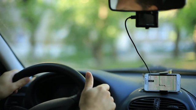 A man gets into the car and turns on the navigator on the smartphone