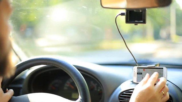 A man gets into the car and turns on the navigator on the smartphone