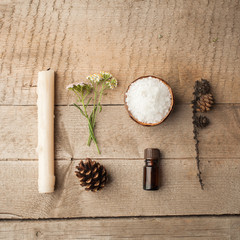 Fototapeta na wymiar Spa and wellness setting with sea salt, oil essence, cones and candle on wooden background. Fall autumn wellness concept, Relax and treatment therapy. knolling flat lay