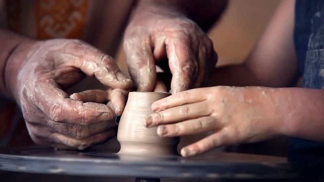 Old man potter teaches his little pupil to make a pot from scratch