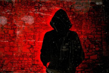 Male figure with hood on red wall background. Hacker concept.