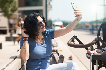 Frau mit Kinderwagen macht ein Foto von sich draußen
