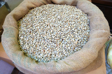 Green unroasted coffee beans in burlap sack.
