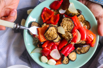 Woman hands holds roasted grilled vegetables (Ratatouille) with eggplant, red pepper, onion,...