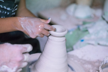 Fototapeta na wymiar Ceramic dishes in working process. Creating ceramic pieces. Tradicional ceramic factory in spain. Father teaching the art of ceramic making.