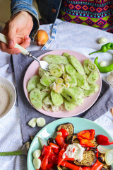 Woman hands tastes with fork green fresh cucumber salad with onion rings spices, herbs, garlic and unrefined oil. Raw vegan lunch, vegetarian healthy dinner