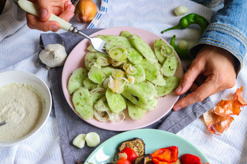 Woman hands tastes with fork green fresh cucumber salad with onion rings spices, herbs, garlic and unrefined oil. Raw vegan lunch, vegetarian healthy dinner