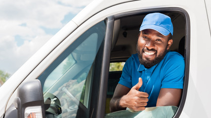 smiling african american delivery man showing thumb up from van