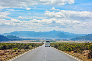 Road in the middle of natural mountain landscape with a van and car on the road with blue sky background