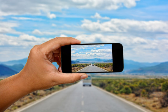 Take a photo with a mobile phone in Road in the middle of natural mountain landscape with a van and car on the road with blue sky background