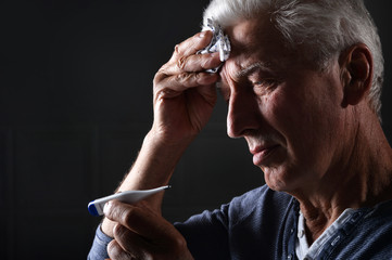 Portrait of sick senior man with thermometer