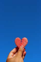 Man holding EXOTIC watermelon slice in shape of heart against blue sky