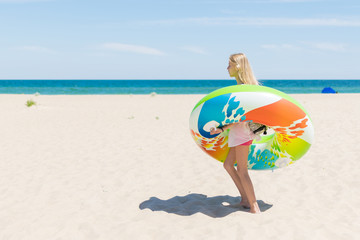 The teenage girl goes with an inflatable circle on the beach by the sea, the ocean.
