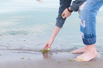 Rest on the sea, the ocean. A woman in jeans touches the water.