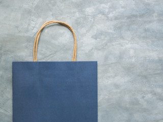 Top view blue paper shopping bag on wall concrete texture background, Mock-up of blank blue paper shopping bag and copy space. Flat lay.