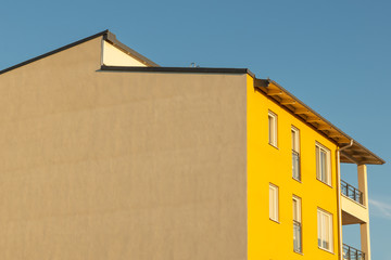 Exterior of a yellow apartment building a summer day with blue sky