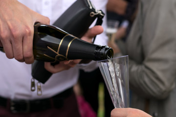 the hand of the man in the white shirt pours champagne on a holiday in the open air